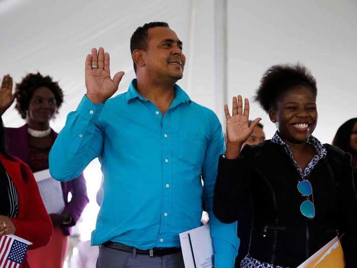 Another smiling group raises their hand to take the Naturalization Oath of Allegiance during a ceremony in Salem, Massachusetts.