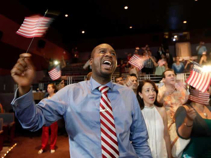 Jean Naason waves his flag and smiles during a naturalization ceremony in Miami.