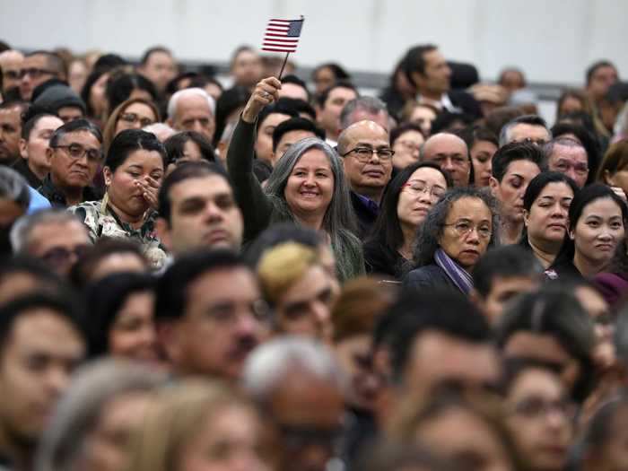 The naturalization ceremony is joyful for those who have been through the long process to become a citizen. Pictured, a new citizen smiles and waves her flag among a crowd in Los Angeles.