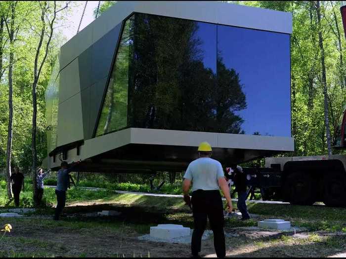 A crane drops the house into place, and it