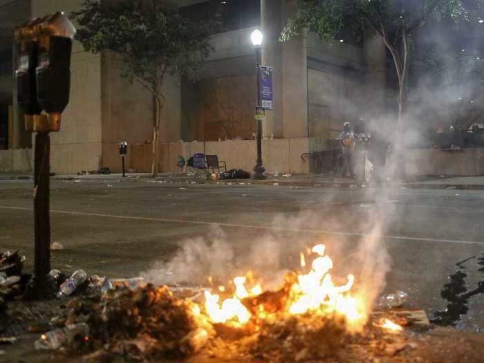 In this scene, a trash fire burns across from the city