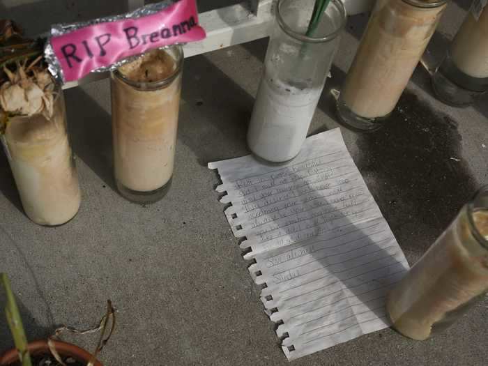 Candles hold a note in place on the ground as part of the memorial for Taylor.