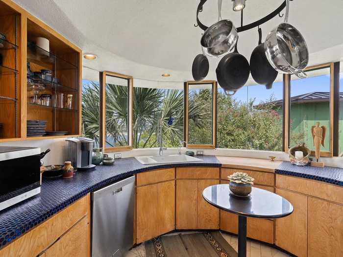 A curved kitchen with a blue-tiled countertop protrudes out over a lower deck ...