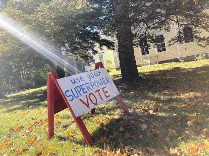 The back of this double-sided sign reads "Use your superpower. Vote."