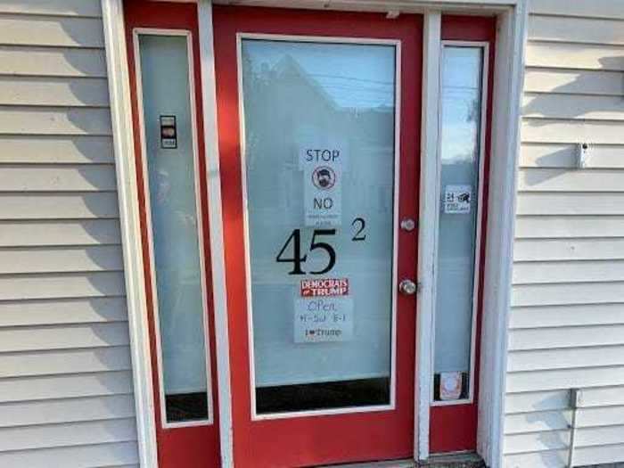 A coffee shop in neighboring Rockland displays a "No Masks Allowed in Store" sign, "Democrats for Trump" bumper sticker, and "I Heart Trump" sign on its front door.