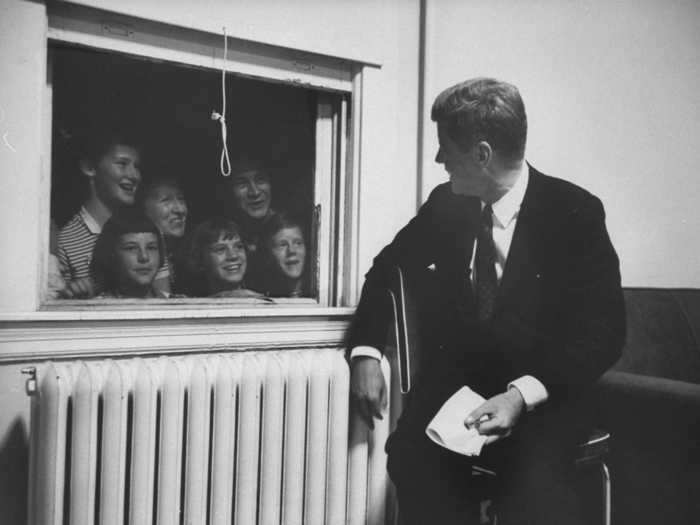 Children peeked in through a window while John F. Kennedy worked on a speech during a campaign stop in Baltimore in 1960.