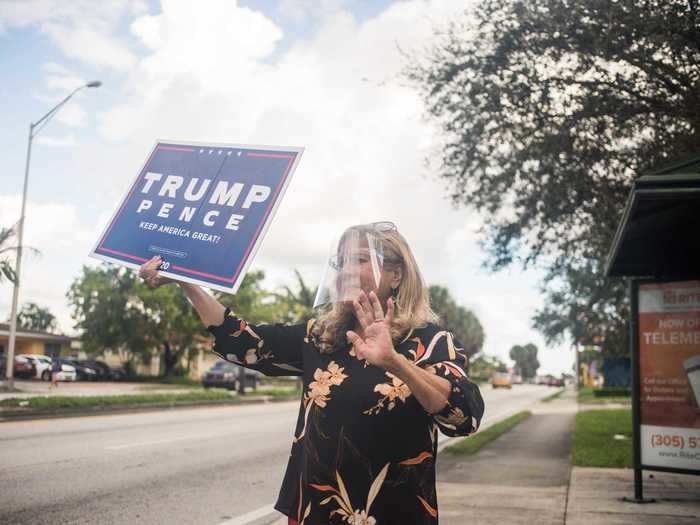 A woman waves a Trump sign in front of the Hialeah Public Library polling location in Hialeah, Florida, on November 1, 2020.