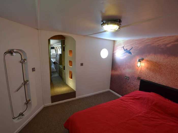 The double bed is surrounded by aviation-themed designs on the wall.