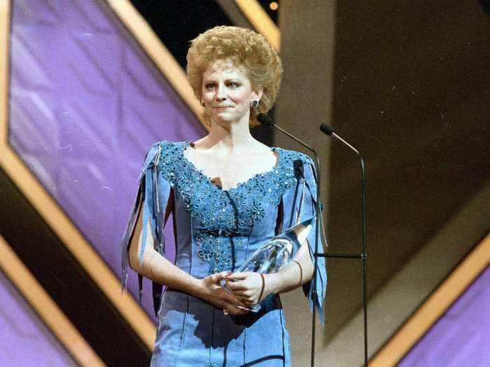 Reba McEntire wore a blue dress in a similar shade with cutouts and fringed sleeves to accept the Entertainer of the Year award in 1986.