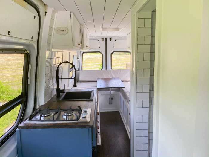 The van also has a kitchen, complete with a faucet, a stovetop, and a refrigerator.