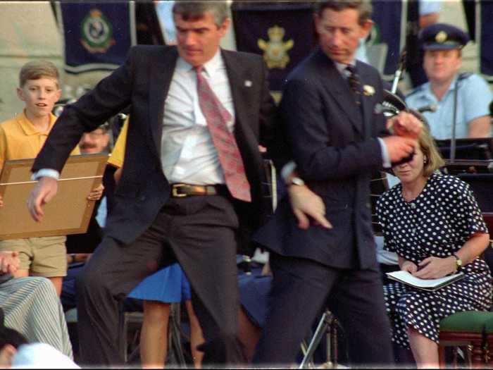 1994: In this photo taken in Sydney, Australia, Prince Charles is pushed to safety by security personnel after 24-year-old student David Kang fired two blank rounds from a starter gun at him. Kang was protesting the treatment of Cambodian asylum seekers in Australia.