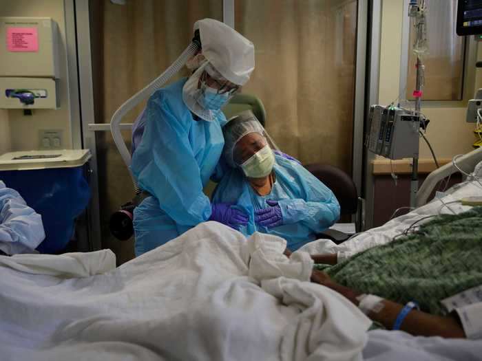 July 31: Romelia Navarro was comforted by a nurse as she wept at the bedside of her husband in St. Jude Medical Center