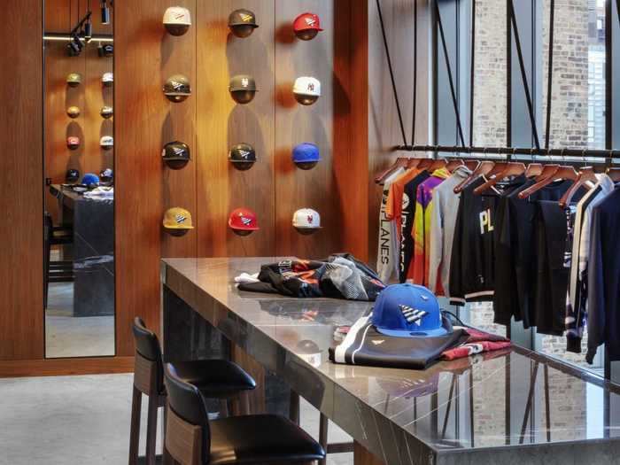 The showroom has a grey marble countertop with a custom hat display and clothes hanging systems.