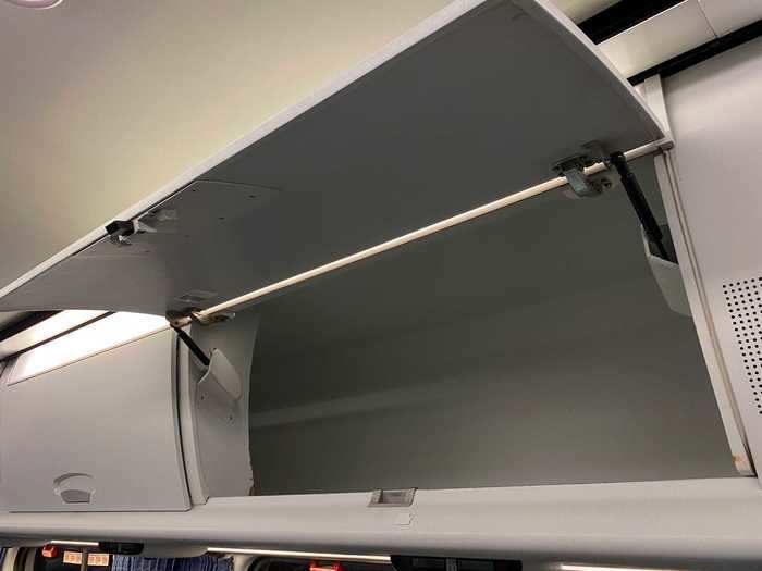 Above the seats are airline-style overhead bins for hand luggage and smaller items.