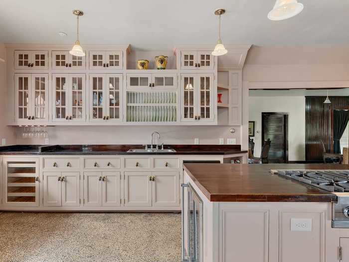 The kitchen has a large island, multiple stovetops, and several walls devoted to storage space.