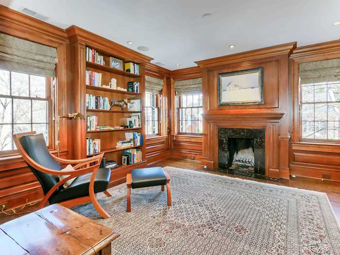 A wood-paneled library includes an attached powder room, a fireplace, and a wet bar.