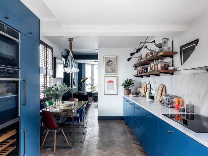 The deli-style kitchen has an open-plan layout with pops of blue color and white marble counters