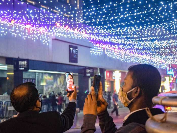 People in Kolkata, India, connected with others virtually while surrounded by colorful light displays on Christmas Eve.
