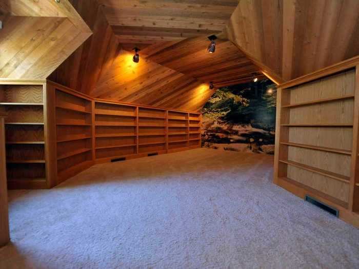 Walking down a hallway will lead you to another bedroom with white carpeting and walls lined with shelves.