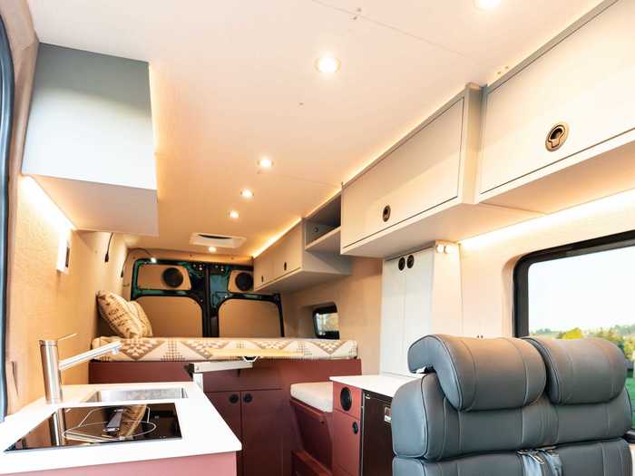 … and the bed platform, additional table, and cushioned seats are by the rear of the camper van.