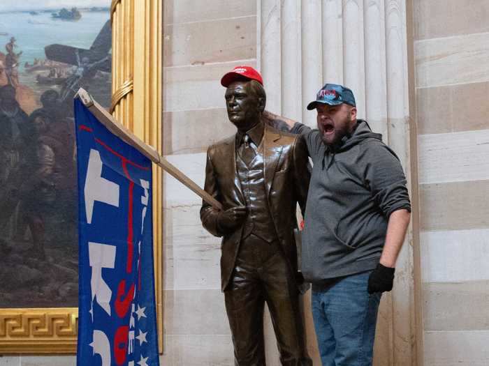 A Trump supporter climbed on stop of a statue of President Gerald R. Ford with a Trump flag and a "Make America Great Again" hat.