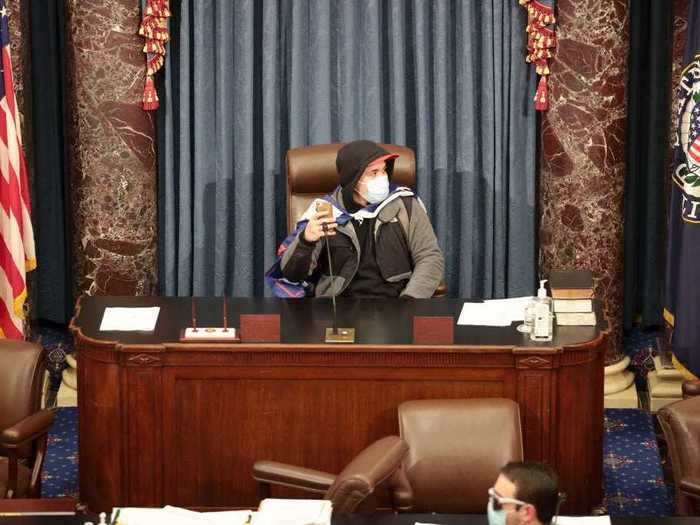 A protester sat in the head chair of the Senate Chamber where Vice President Mike Pence had sat shortly before.