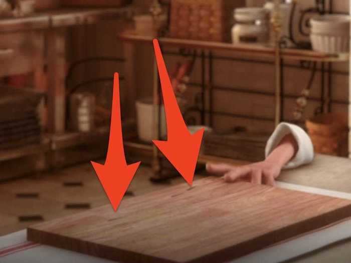There are slit marks on the cutting board after Colette pulls knives out of it.