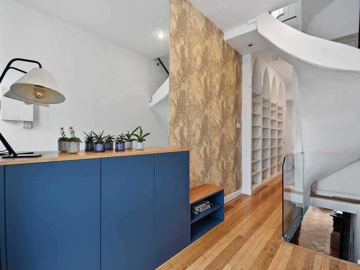 The entrance hallway has cabinets and shelves on one side, using white walls and mirrors to create more space.