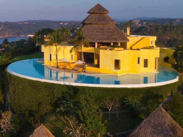 The pool, a 360-degree infinity pool that blends into the mountainside, is a major feature of the bright-yellow, sunlit property.