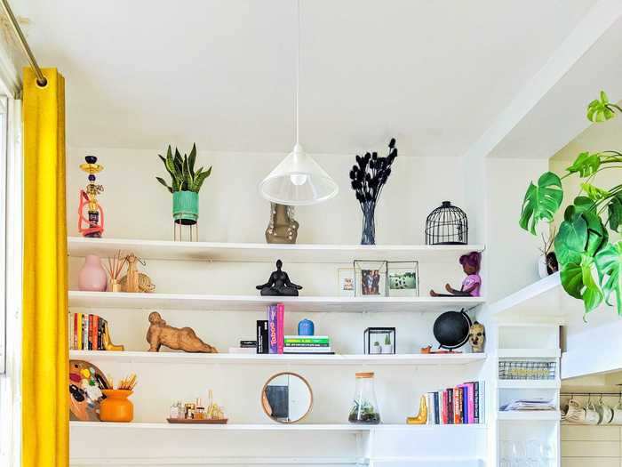 Christian filled the built-in shelves with plants, perfumes, photos, figurines, books, and a mirror to make the room feel larger.