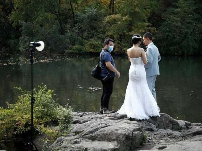 Wedding photographers wear face masks and keep their distance while posing couples.