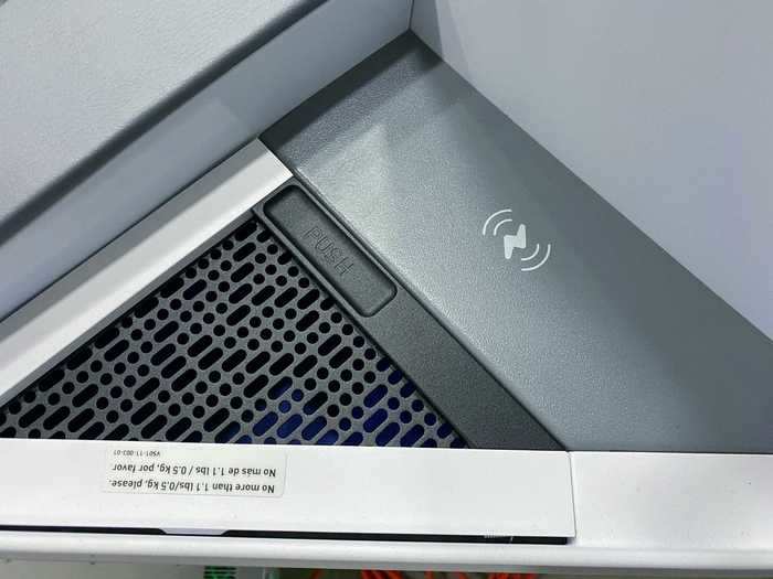 Storage space is also a key element and directly next to the charger is a small latched compartment. Note the Morse code compartment cover, a trend that JetBlue started on the Airbus A220.