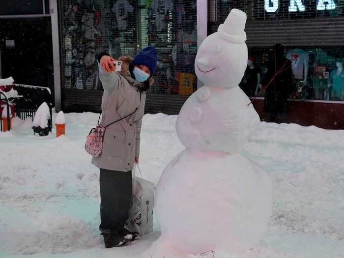 A woman posed for a selfie with a snowman.