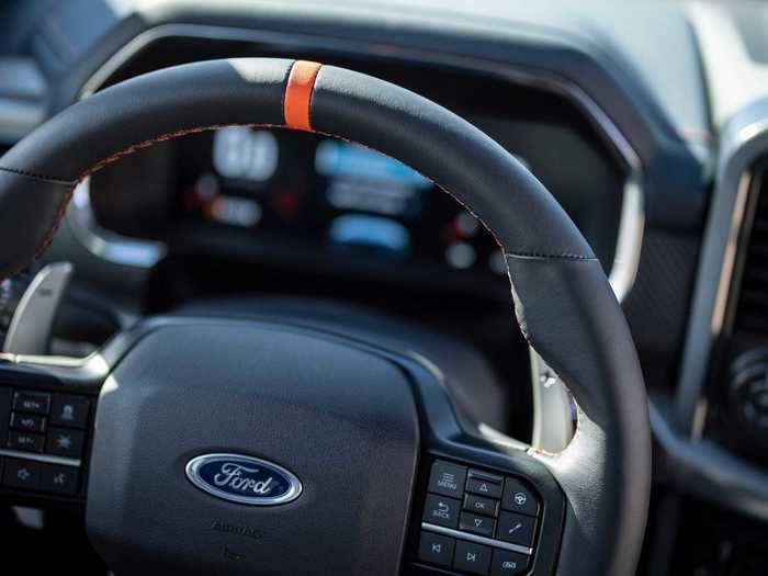 The steering wheel has a top centering mark, aluminum paddle shifters, and a laser-etched logo.