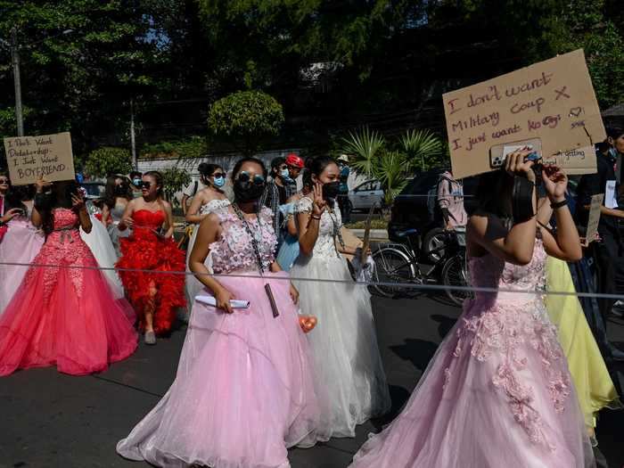 A group of women dressed up in wedding dresses. One carried a sign that said, "I don