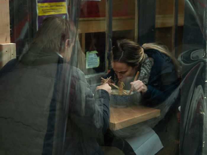 Plastic dividers and heaters make dining Covid-friendly and warm while guests enjoy their meals on the streets in front of restaurants.