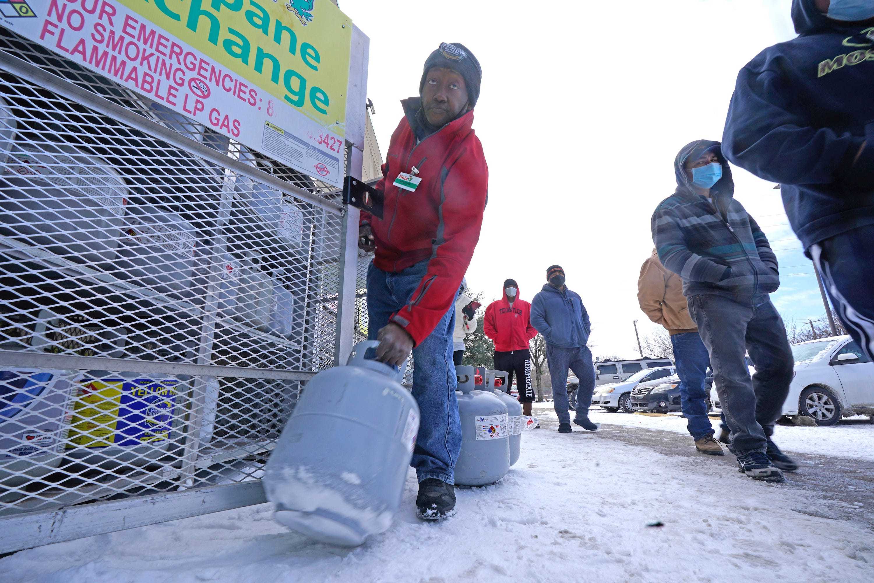 Robert Webster pulls a full canister of propane for sale as customers line up to enter a grocery store Tuesday, Feb. 16, 2021, in Dallas. Even though the store lost power, it was open for cash only sales.