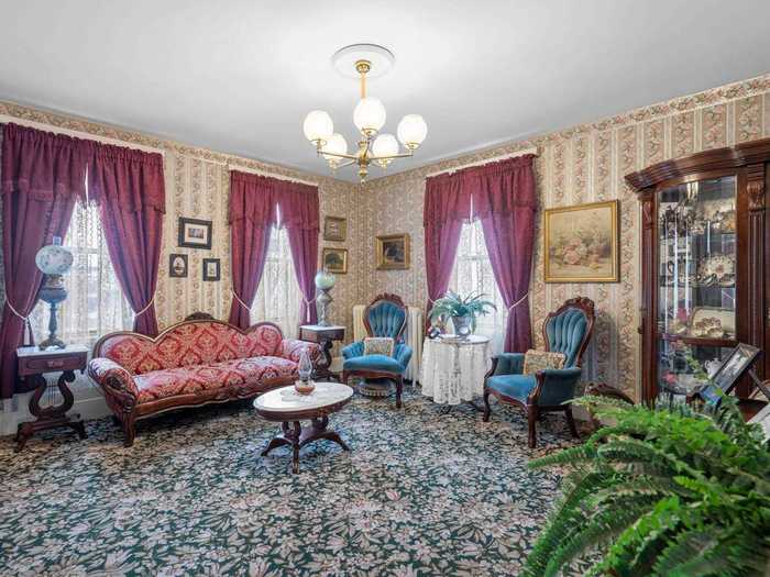 The living room has floral wallpaper and stately drapes. It