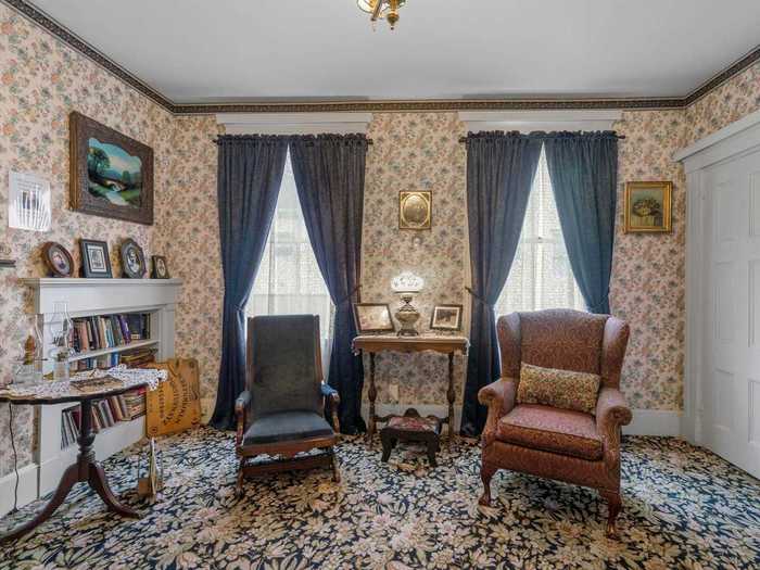 The dining room flows into the sitting room, which has a fireplace, a stocked bookshelf, and a large black sofa.