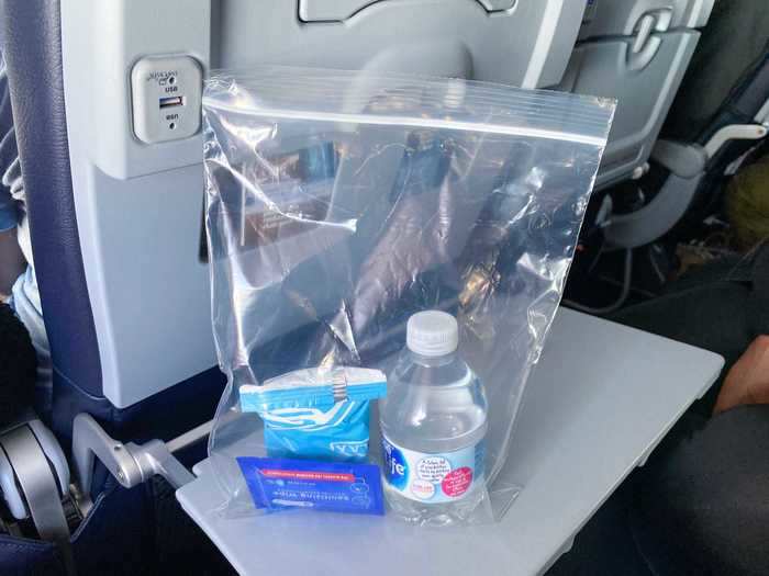 With the suspense of takeoff behind us, the flight attendants began the usual in-flight service. On this flight, a snack bag with pretzels, a water bottle, and a sanitary wipe were distributed.