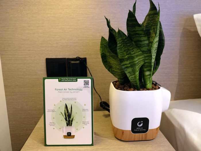 On the bedside table is a pop of greenery in the form of a live plant with ionizing technology that claims to clean airborne pollutants and reduce anxiety and lethargy.