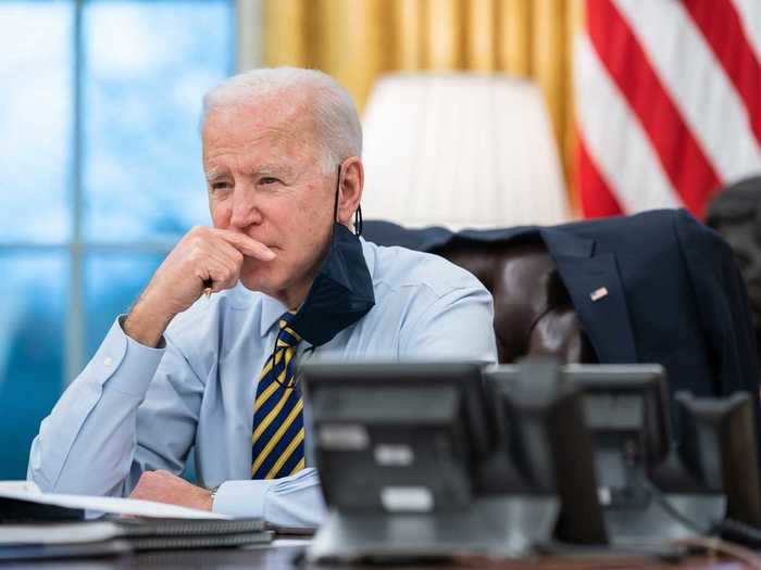 Biden dangles a mask on his ear while on a call with governors in states impacted by snow storms.