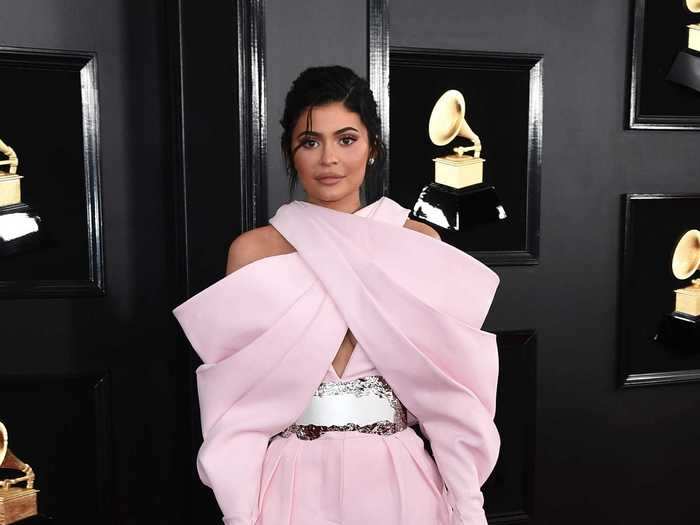Kylie Jenner arrived fashionably late wearing a baby-pink Balmain couture suit.