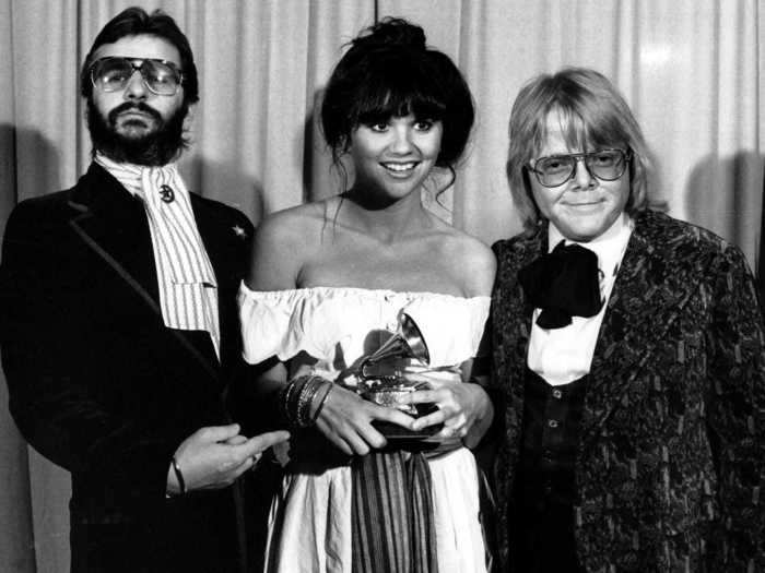 February 1977: Linda Ronstadt - flanked by Ringo Starr and Paul Williams - wore an incredibly chic off-the-shoulder dress while holding her Grammy.