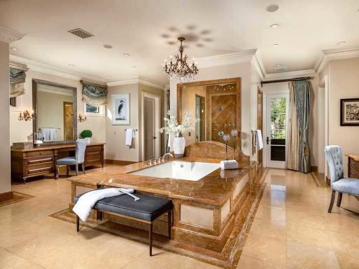 Connected to the bedroom is an extravagant bathroom that has a bathtub and multiple vanities.