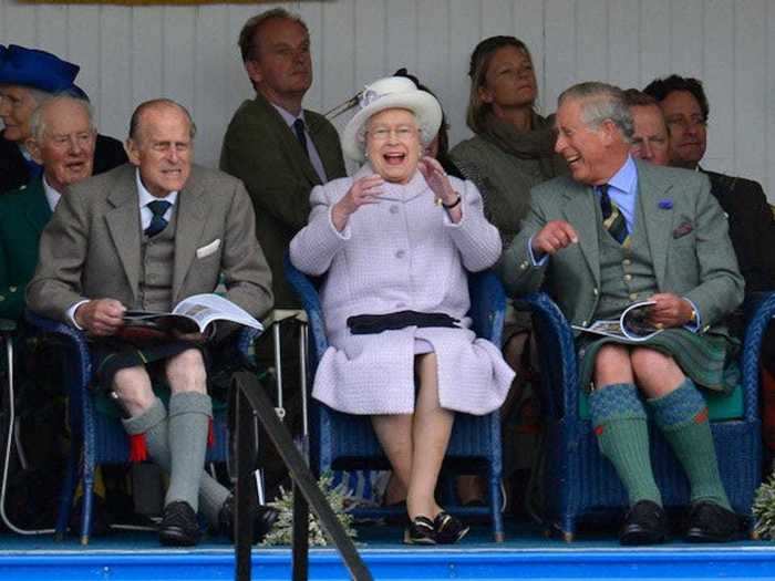 2012: This brilliant photo captures Philip, Elizabeth, and Charles laughing as they watch the Braemer Gathering in Scotland as competitors participated in a sack race.