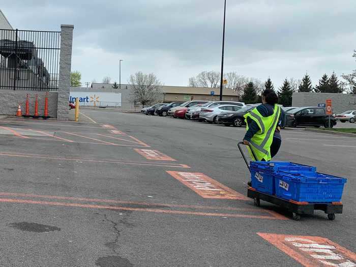 Walmart shoppers use small carts to pull crates with grocery orders.