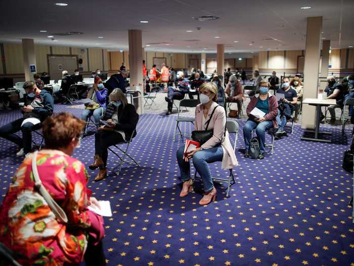 After they get their shots, people sit in socially distanced seats above a star-lined carpet, which may be reminiscent of Disney