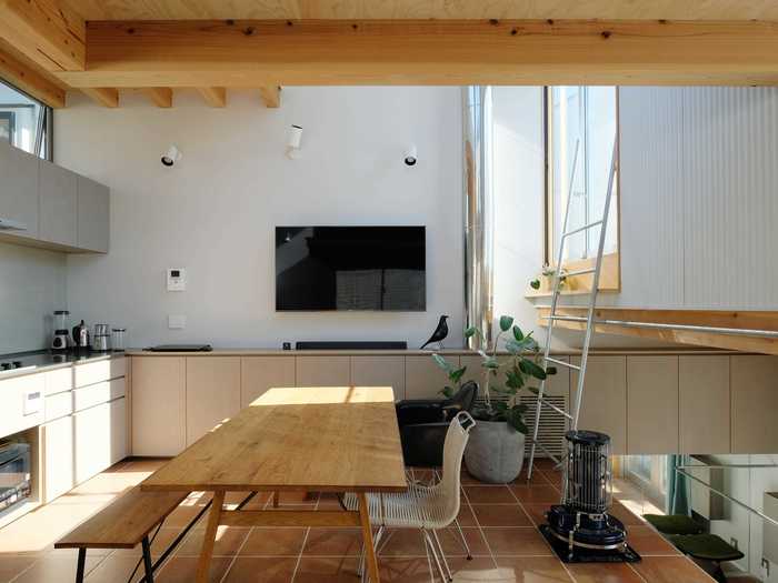 The kitchen and living room sits under exposed wooden beams intentionally left bare by UNEMORI ARCHITECTS.