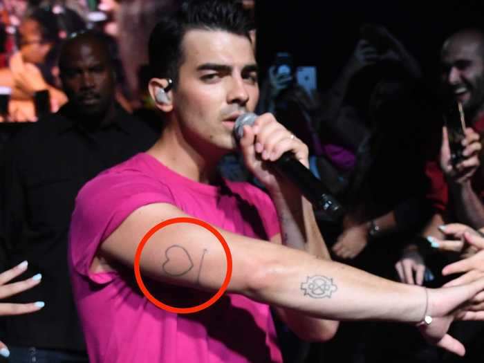 Joe has a heart with an arrow below it on the back of his right arm.